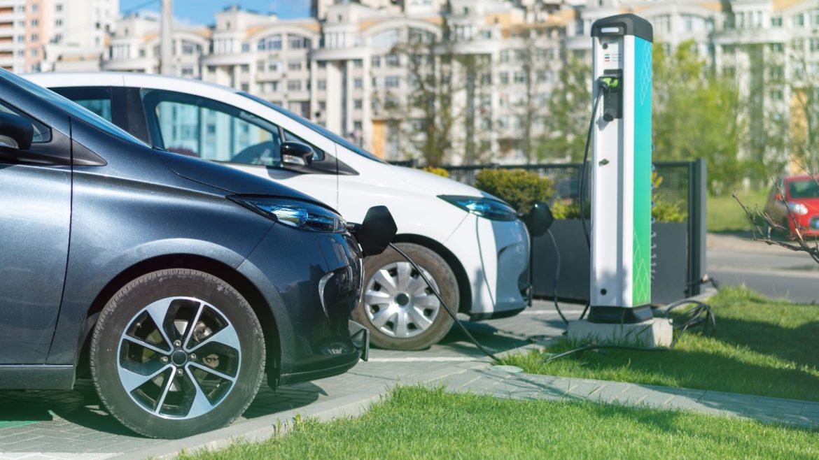 Two electric cars charging at a public charging station in a city